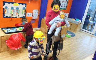 Playful children and caregiver at Monkey Puzzle Day Nursery Enfield, engaging in fun activities in a bright, colorful classroom environment.