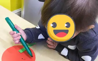 Green marker, child drawing on red paper, preschool art activity, Monkey Puzzle Day Nursery Enfield, early childhood creative crafts.