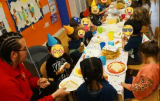 4_1764 Children celebrating birthday party at Monkey Puzzle Day Nursery Enfield, wearing party hats and enjoying cake indoor setting.