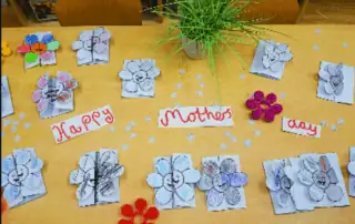 Colorful handmade Mother’s Day cards and flowers on a classroom table at Monkey Puzzle Day Nursery Enfield, celebrating motherhood with children's crafts and a cheerful atmosphere.