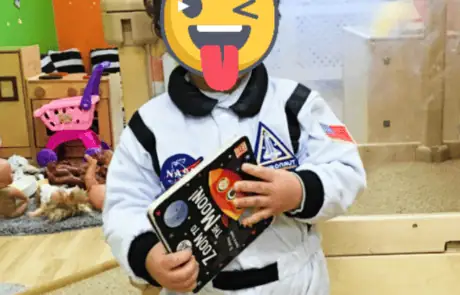 Rocket ship book astronaut costume, toddler playing in nursery, educational preschool activities, engaging early childhood learning, Monkey Puzzle Day Nursery Enfield.