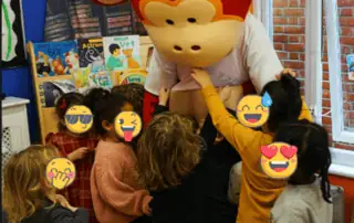 7_33613 Monkey Puzzle Day Nursery Enfield children engaging with a friendly mascot in a lively indoor setting, promoting fun and learning for early childhood development.
