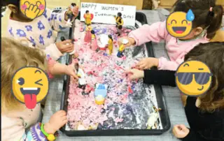 Colorful children's hands engaging in a sensory activity with rice and figurines at Monkey Puzzle Day Nursery Enfield, celebrating International Women's Day.