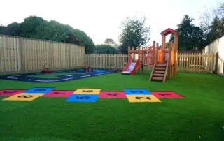 climbing equipment and garden at monkey puzzle enfield Colorful outdoor play area at Monkey Puzzle Day Nursery Enfield with slide, hopscotch, and tricycles.