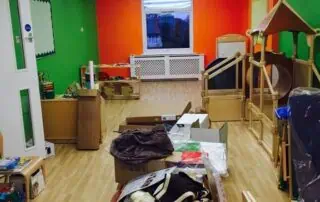 open spaces at monkey puzzle enfield Bright and colorful indoor playroom at Monkey Puzzle Day Nursery Enfield, featuring vibrant green and orange walls, a cozy wooden playhouse, and various toys and learning materials for early childhood development.