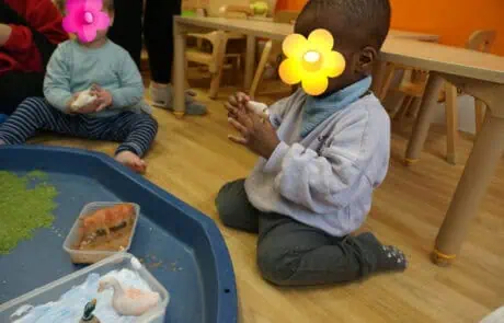 Colorful young children engaging in sensory play with toy animals at Monkey Puzzle Day Nursery Enfield, fostering creativity and early childhood development in a warm, inviting environment.