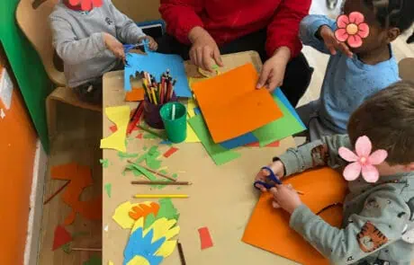 Colorful paper crafts activity with children and caregiver at Monkey Puzzle Day Nursery Enfield, fostering creativity and early learning in a nurturing environment.