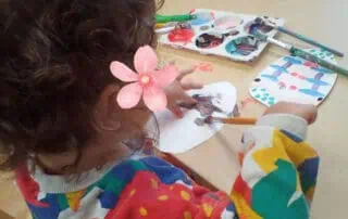 Colorful child engaging in creative painting activity at Monkey Puzzle Day Nursery Enfield, offering a safe and nurturing environment for early childhood development.