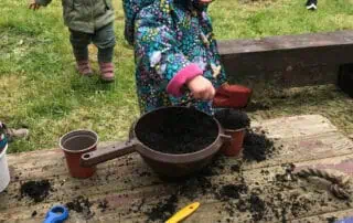Colorful children's outdoor gardening activity at Monkey Puzzle Day Nursery Enfield with kids planting seeds and exploring nature.