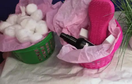 Soft pink and green baskets with plush toys, skincare products, and a hairbrush, set on a white cloth, representing a cozy, nurturing environment at Monkey Puzzle Day Nursery Enfield.