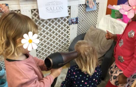 Blow-drying hair in a children's salon at Monkey Puzzle Enfield childcare, focusing on fun grooming activities for kids.