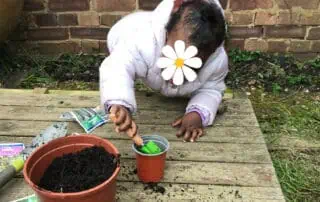 Child planting seeds outdoors at Monkey Puzzle Day Nursery Enfield, engaging children in gardening activities and outdoor exploration.