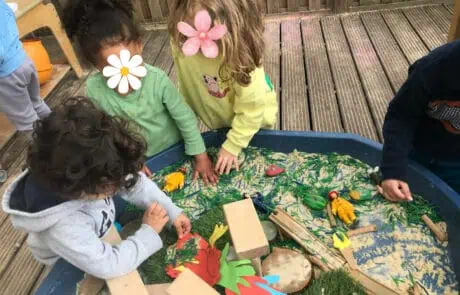 Colorful children playing and exploring a sensory water table at Monkey Puzzle Day Nursery Enfield, featuring outdoor play, safe environment, and early childhood development activities.