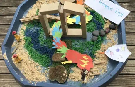 Sand and water play table with mini figures and themed decorations for St. George's Day at Monkey Puzzle Day Nursery Enfield, encouraging imaginative learning.