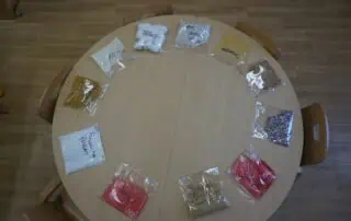 Colorful sensory play items in plastic bags arranged in a circle on a wooden table at Monkey Puzzle Day Nursery Enfield, promoting early childhood development and tactile learning experiences.