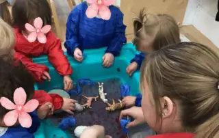 Colorful toddler water play activity at Monkey Puzzle Day Nursery Enfield, children engaging with toy figures and sensory water in a safe indoor environment.