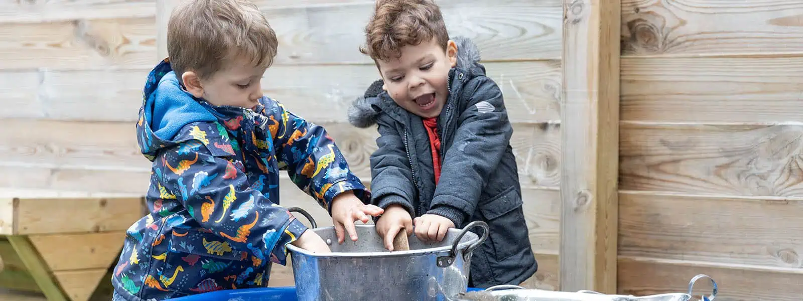 Colorful toddlers playing and learning outdoors at Monkey Puzzle Day Nursery Enfield, engaging in hands-on activities to promote preschool development and early childhood education.