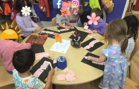 Brightly dressed children engage in arts and crafts activities at Monkey Puzzle Day Nursery Enfield, creating colorful paper projects in a vibrant and nurturing early childhood education environment.