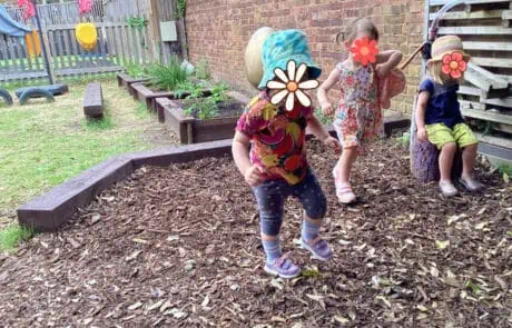 Colorful young children playing outdoors in the garden at Monkey Puzzle Day Nursery Enfield, engaging in outdoor play and exploration.