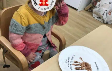 Monkey Puzzle Day Nursery Enfield child enjoying a creative activity with a painted paper plate and a cute animal image.