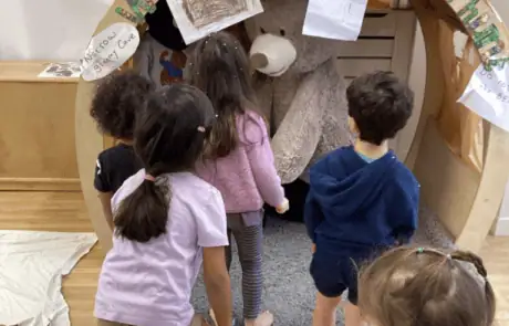 Small children engaging with a teddy bear mascot at Monkey Puzzle Day Nursery Enfield, fostering imagination and social skills.