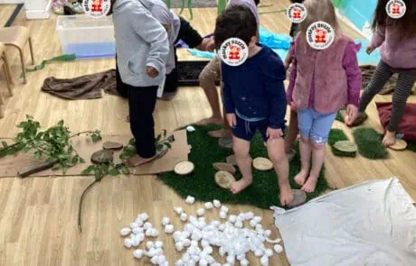 Wooden log slices with children playing adventure-themed indoor area at Monkey Puzzle Day Nursery Enfield.