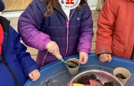 Kids planting seeds in sensory activity at Monkey Puzzle Day Nursery Enfield for early childhood development and learning.