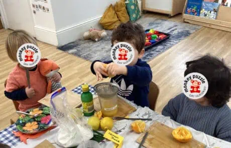 Children engaging in a sensory activity with citrus fruits at Monkey Puzzle Day Nursery Enfield, fostering early learning and development in a safe, nurturing environment.