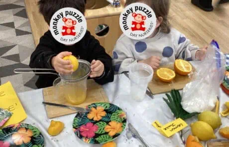 Freshly prepared orange juice by children at Monkey Puzzle Day Nursery Enfield, engaging in fun and educational activities, showcasing a vibrant learning environment for early childhood development.