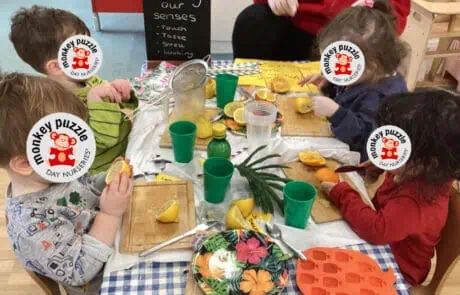 Lively children engaging in sensory play with lemon slices and weather-themed decorations at Monkey Puzzle Day Nursery Enfield.