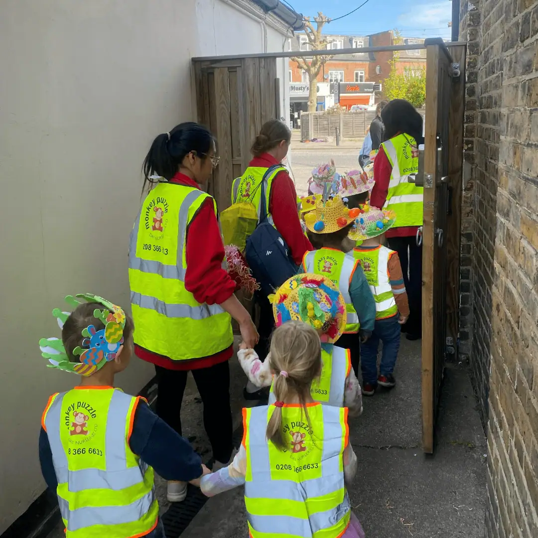 Monkey Puzzle Day Nursery Enfield children walking outside in colorful hats and high-vis vests.