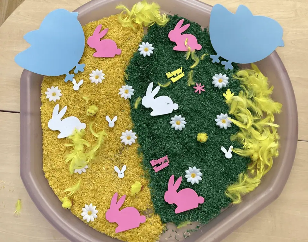Colorful Easter-themed sensory activity at Monkey Puzzle Day Nursery Enfield featuring bunny and egg cutouts, artificial grass, and vibrant decorations for early childhood learning.