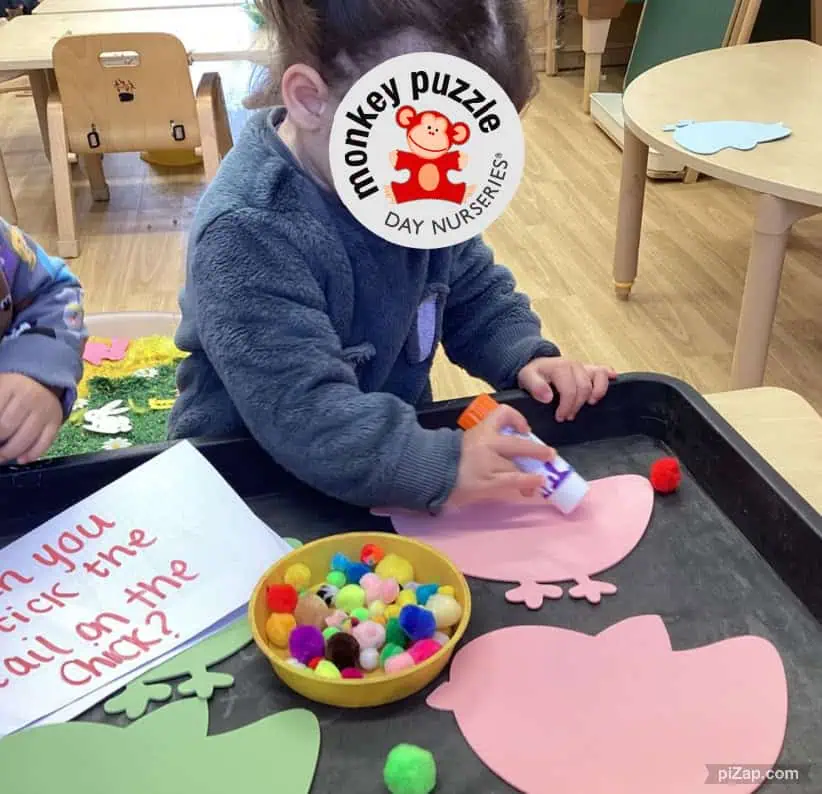 Green, yellow, and pink paper pig crafts used for a children’s activity at Monkey Puzzle Day Nursery Enfield, featuring craft materials and children engaging in playful learning.