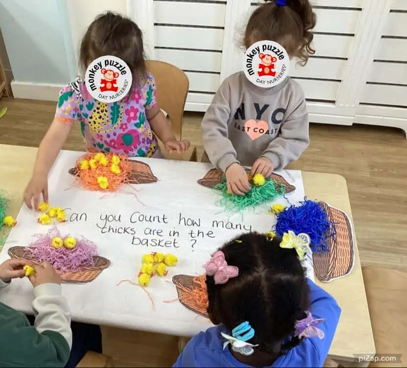 Chick counting activity at Monkey Puzzle Day Nursery Enfield, children engaging in educational play with colorful chicks and baskets, fostering early math skills and social interaction in a welcoming nursery environment.