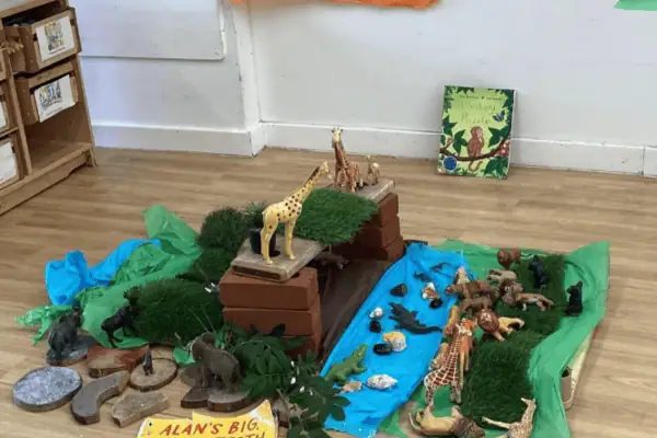 Giraffe, zebra, and elephant figurines on a mini jungle scene at Monkey Puzzle Day Nursery Enfield, with lush greenery and animal toys for early childhood development.