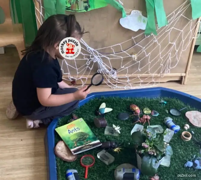 Magnifying glass exploring bug habitat at Monkey Puzzle Day Nursery Enfield, fostering curiosity and sensory learning for children.
