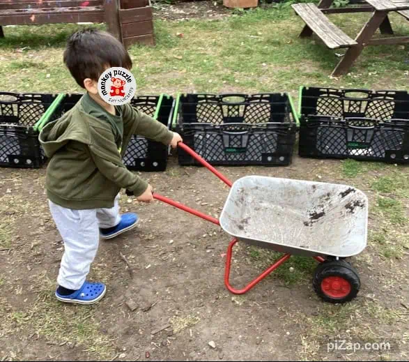 Wheelbarrow activity with young child at Monkey Puzzle Day Nursery Enfield, innovative outdoor play and learning environment.