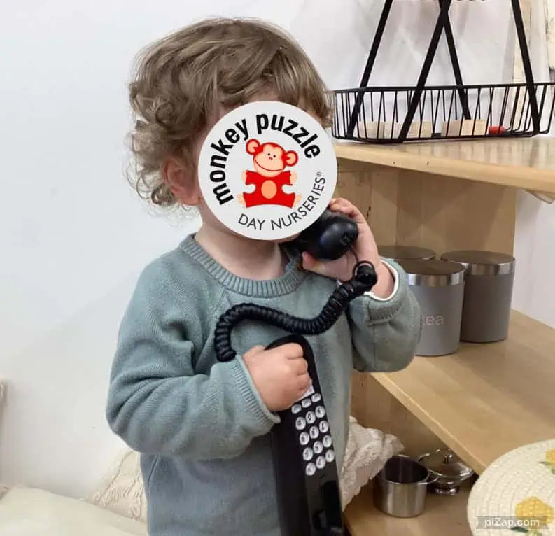 Monkey puzzle day nursery enfield child playing with toy telephone indoors.