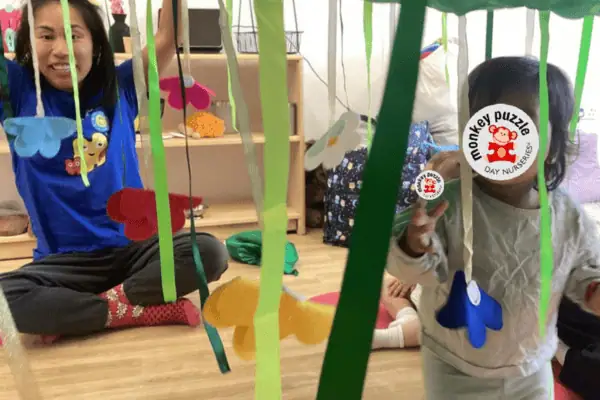 Monkey Puzzle Day Nursery Enfield children engaging in fun, creative activities with colorful streamers and toys, highlighting a nurturing and stimulating early learning environment in Enfield.