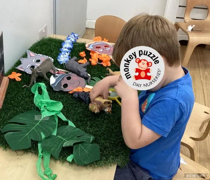 Monkey Puzzle Day Nursery Enfield children engaging in imaginative play with animal-themed toys and props on a lush green mat.