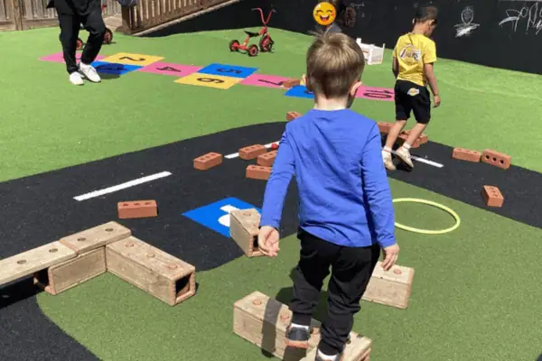 Boy playing with building blocks at Monkey Puzzle Day Nursery Enfield, outdoor playground for early childhood education.