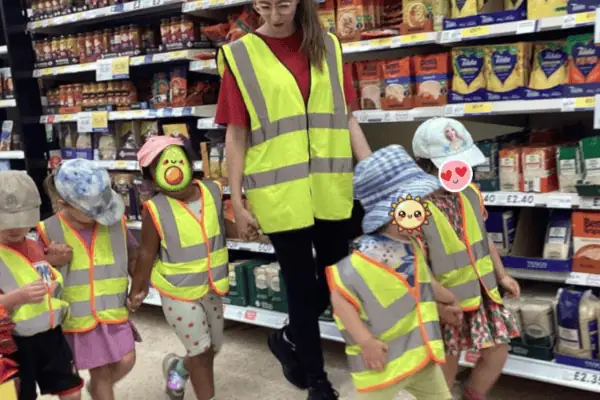 High visibility safety vests worn by preschool children on educational trip at supermarket aisle at Monkey Puzzle Day Nursery Enfield.