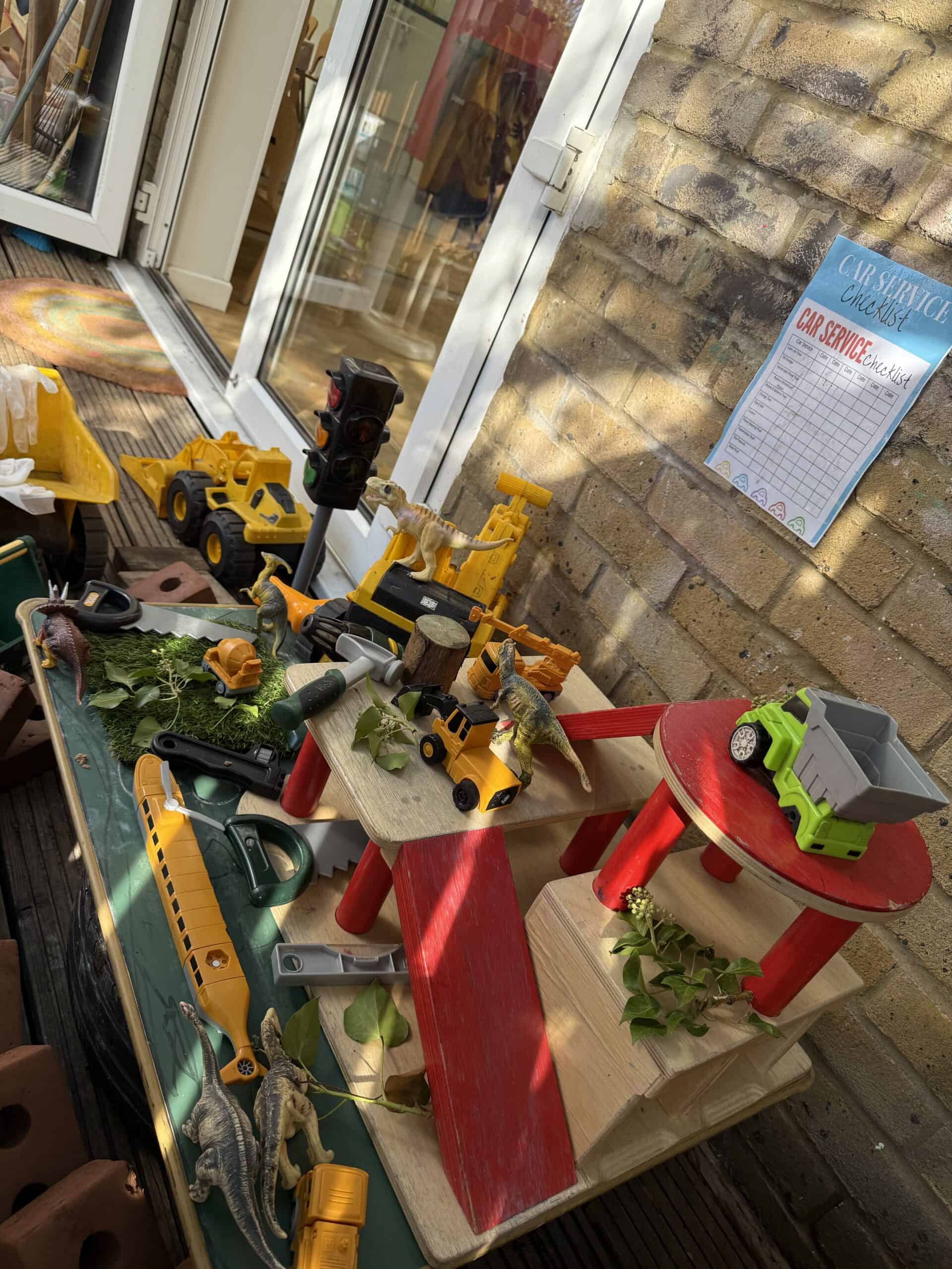 Toy construction vehicles and play tools arranged on a colorful play table at Monkey Puzzle Day Nursery in Enfield, fostering imaginative play and early childhood development.