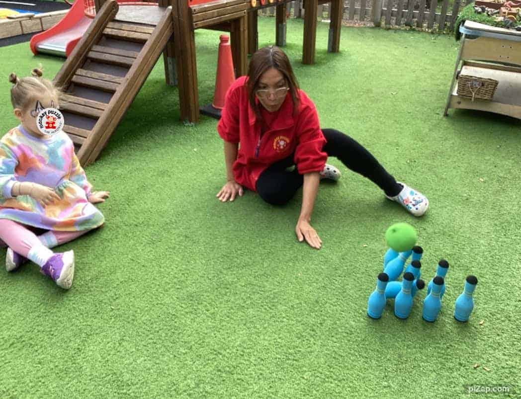 Colorful toddler playing with outdoor bowling game at Monkey Puzzle Day Nursery Enfield, showcasing a safe and engaging play area for children.
