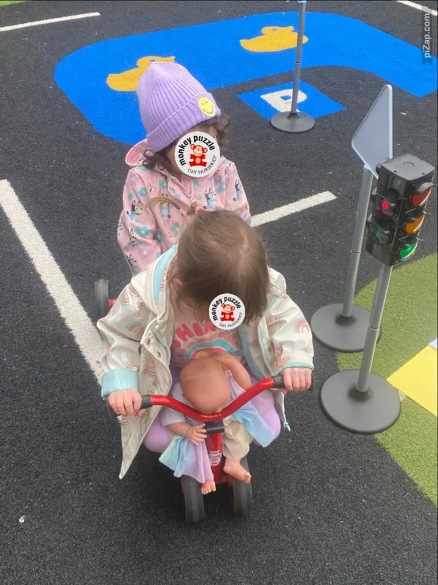 Monkey Puzzle Day Nursery Enfield children playing outside on a colorful playground with traffic light and hopscotch markings, promoting safe and engaging outdoor activities for early childhood development.
