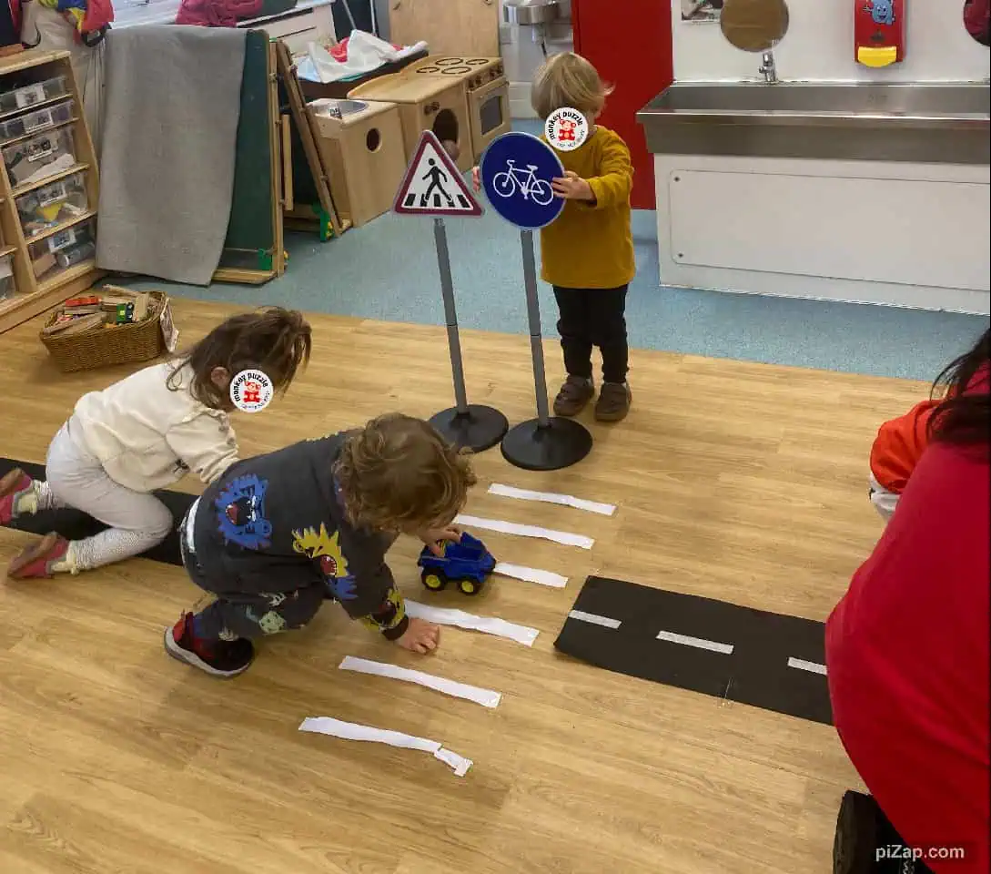 Driving simulation activity in a preschool classroom at Monkey Puzzle Day Nursery Enfield, focusing on road safety and traffic signs for early childhood development.